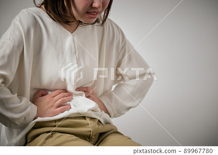 一個有胃痛并且可以握住她的手的年輕女人 一個有胃痛并且可以握住她的手的年輕女人 89967780