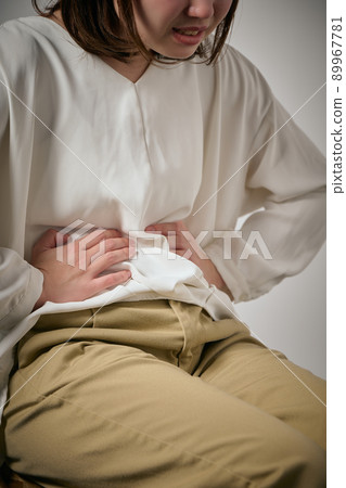 A young woman who has a stomachache and can hold her hands 89967781