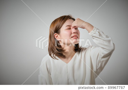 一個年輕的女人,她的眉毛疼痛,可以用手指握住它 一個年輕的女人,她的眉毛疼痛,可以用手指握住它 89967787
