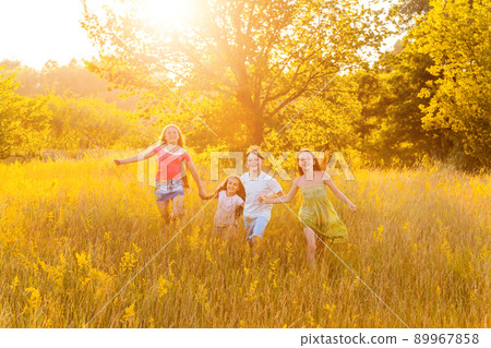 four happy beautiful children running playing moving together in the beautiful summer day. jumping and looking at camera with happiness and toothy smile. 89967858