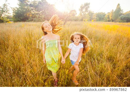 two sisters enjoying together at summertime. jumping and running in the park on sunset and happy two sisters enjoying together at summertime. jumping and running in the park on sunset and happy 89967862
