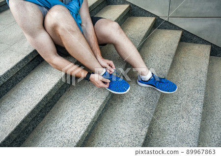 Side view. Tie shoelaces. pause after running. Outdoor shot Side view. Tie shoelaces. pause after running. Outdoor shot 89967863