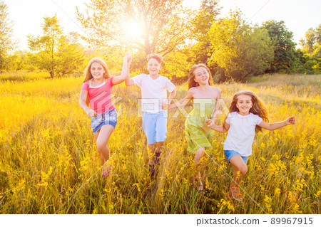 four happy beautiful children running playing moving together in the beautiful summer day. jumping and looking at camera with happiness and toothy smile. four happy beautiful children running playing moving together in the beautiful summer day. jumping and looking at camera with happiness and toothy smile. 89967915