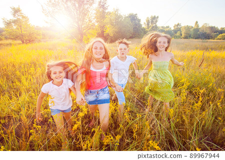 four happy beautiful children running playing moving together in the beautiful summer day. jumping and looking at camera with happiness and toothy smile. four happy beautiful children running playing moving together in the beautiful summer day. jumping and looking at camera with happiness and toothy smile. 89967944