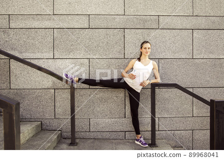 Fitness beautiful woman with freckles on her face drinking water and sweating after exercising in city. Female athlete after work out. looking at camera and smilling. 89968041