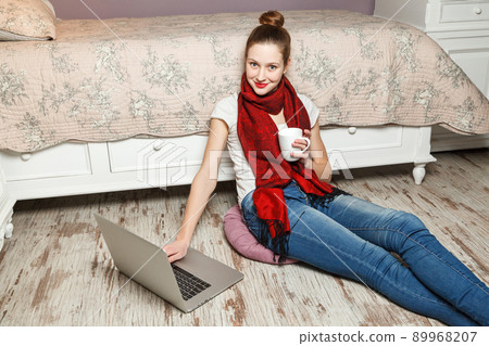 Ecommerce woman. Young female using computer for online shopping, sitting on the floor and drinking coffee. Ecommerce woman. Young female using computer for online shopping, sitting on the floor and drinking coffee. 89968207