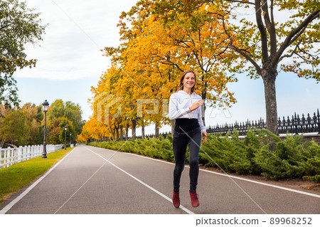 Close up. Healthy woman jogging in autumn park. Outdoor shot Close up. Healthy woman jogging in autumn park. Outdoor shot 89968252