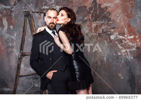 Closeup bearded blonde businessman and foxy woman standing near stepladder. Studio shot, isolated on shabby wall Closeup bearded blonde businessman and foxy woman standing near stepladder. Studio shot, isolated on shabby wall 89968377