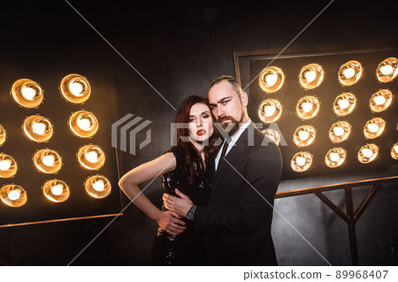 Attractive, famous couple in the luxurious night club hugging and looking at camera. Studio shot 89968407