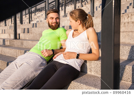 Young sporty couple are resting and check their fitness watch together. sport and technology concepts. 89968416