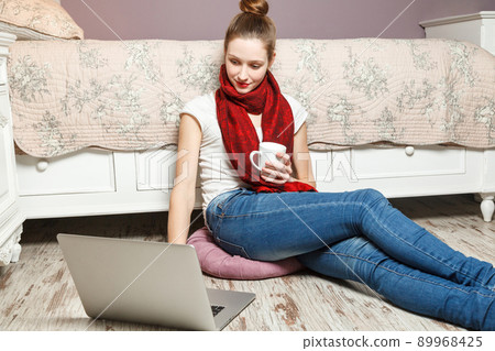 Ecommerce woman. Young female using computer for online shopping, sitting on the floor and drinking coffee. Ecommerce woman. Young female using computer for online shopping, sitting on the floor and drinking coffee. 89968425