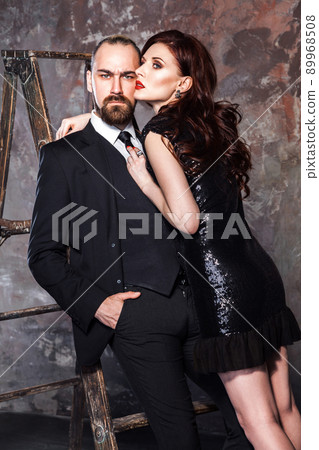 Sensual couple, bearded man and red head woman hugging man . Studio shot, isolated on shabby wall Sensual couple, bearded man and red head woman hugging man . Studio shot, isolated on shabby wall 89968508