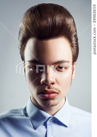 Portrait of young man with retro classic pompadour hairstyle. studio shot. looking at camera. Portrait of young man with retro classic pompadour hairstyle. studio shot. looking at camera. 89968659