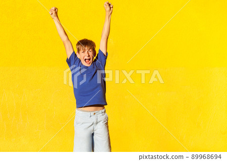 Victory! Emotional freckled boy hands up and shout. isolated on yellow background. Summer 89968694