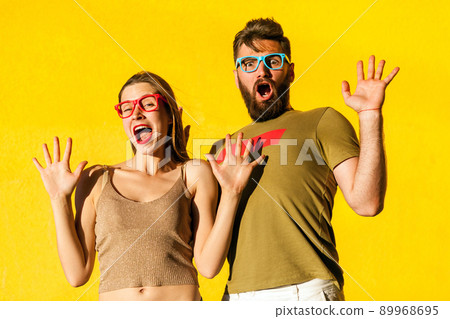 Its not me! Funny couple grimacing, shocked and looking at camera. Isolated on yellow background, studio shot Its not me! Funny couple grimacing, shocked and looking at camera. Isolated on yellow background, studio shot 89968695