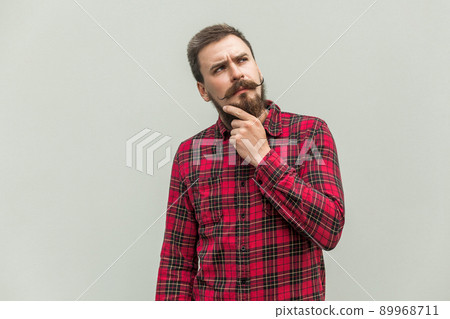 Choosing. Creativity businessman with beard and mustache looking up and thinking. Studio shot, gray background. 89968711