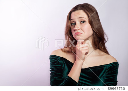 I don't know. Portrait of unhappy thoughtful woman with freckles and classic green dress. studio shot on silver gray background. 89968730