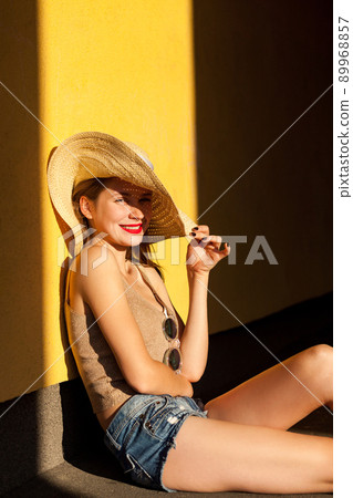 Funny young model sitting on ground, looking at camera and toothy smile. Isolated on yellow background, studio shot Funny young model sitting on ground, looking at camera and toothy smile. Isolated on yellow background, studio shot 89968857