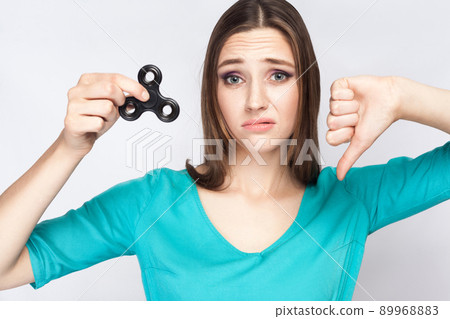 Young beautiful girl holding and playing with fidget spinner. studio shot on white background. Young beautiful girl holding and playing with fidget spinner. studio shot on white background. 89968883