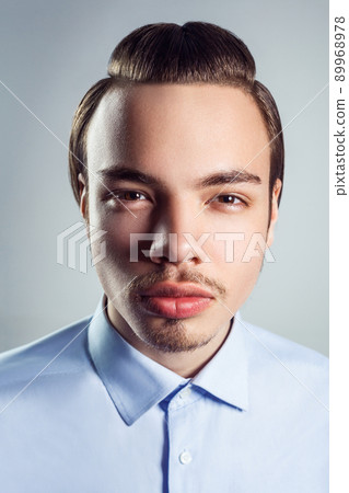 Portrait of young man with top knot hairstyle. studio shot. looking at camera. Portrait of young man with top knot hairstyle. studio shot. looking at camera. 89968978