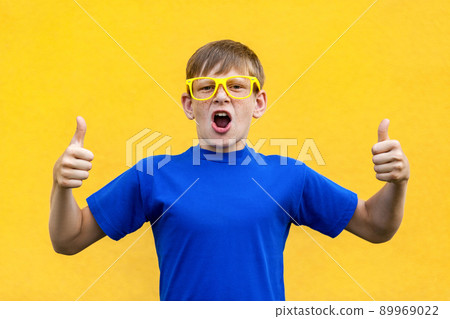 Happiness thumbs up, looking at camera and toothy smile. Studio shot, yellow background 89969022
