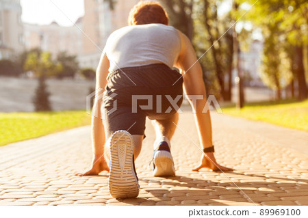 Young athletic man jogging at morning. Low star. Fitness model in crossfit exercise outdoors. Healthy lifestyle concept. 89969100