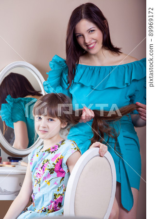 Mother hairdressing her preteen beautiful daughter at home. Mother hairdressing her preteen beautiful daughter at home. 89969172