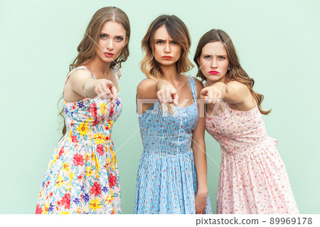 Hey you! Young adult womans, pointing fingers and looking at camera. On green background. Indoor, studio shot Hey you! Young adult womans, pointing fingers and looking at camera. On green background. Indoor, studio shot 89969178