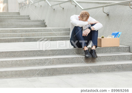 Unhappy red hair and bearded business man siting with cardboard, holing head and feeling sad and cry. Outdoor 89969266