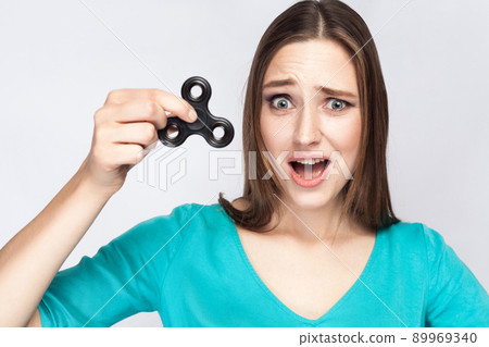 Young beautiful girl holding and playing with fidget spinner. studio shot on white background. 89969340
