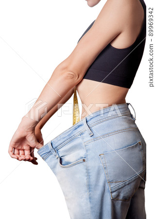 Close-up of slim waist of young woman in big jeans showing successful weight loss, isolated on white background, diet concept. 89969342