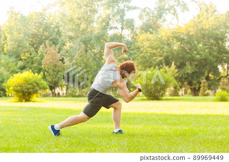 Workout in summer morning. Muscules redhead athlete posing, at camera. Outdoor Workout in summer morning. Muscules redhead athlete posing, at camera. Outdoor 89969449