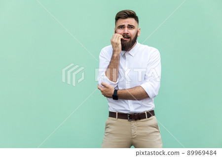 Stylish bearded businessman with warried. Hipster guy having shocked face, looking at camera. Indoor, studio shot, light green background Stylish bearded businessman with warried. Hipster guy having shocked face, looking at camera. Indoor, studio shot, light green background 89969484