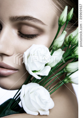 portrait of beautiful model with good skin on white background with white roses flower. portrait of beautiful model with good skin on white background with white roses flower. 89969487