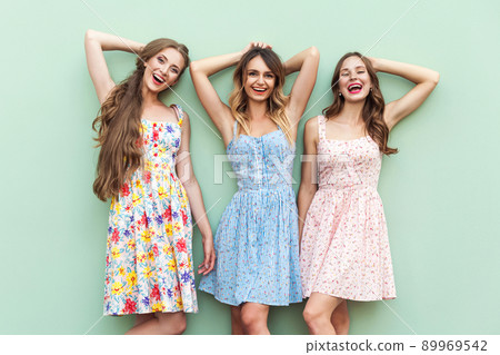 Beautiful girls in dress, standing in front of green background . Hands crossed under head, relaxed after shopping in mall. looking at camera and toothy smiling. Isolated on green background. Studio Beautiful girls in dress, standing in front of green background . Hands crossed under head, relaxed after shopping in mall. looking at camera and toothy smiling. Isolated on green background. Studio 89969542
