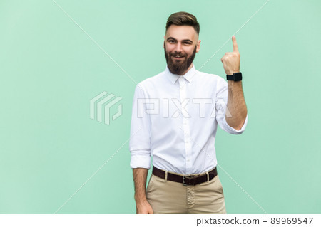 Young adult businessman has an idea, pointing with finger up isolated on light green wall background. Excited guy with solution for a problem. Human face expression body language, life perception 89969547