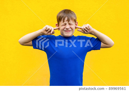 I dont want hear you! Sadness ginger boy holding fingers on ears and closed eyes. Isolated on yellow background I dont want hear you! Sadness ginger boy holding fingers on ears and closed eyes. Isolated on yellow background 89969561