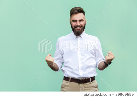 Businessman rejoicing for his success. Isolated on light green background. Indoor, studio shot Businessman rejoicing for his success. Isolated on light green background. Indoor, studio shot 89969699