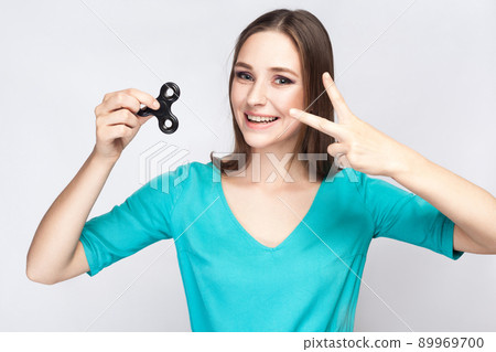 Young beautiful girl holding and playing with fidget spinner. studio shot on white background. Young beautiful girl holding and playing with fidget spinner. studio shot on white background. 89969700