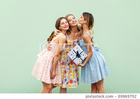 Congratulations with birthday. Kissing. Pretty girls is giving her beautiful young adult friend a present box. Isolated on green background, studio shot Congratulations with birthday. Kissing. Pretty girls is giving her beautiful young adult friend a present box. Isolated on green background, studio shot 89969702