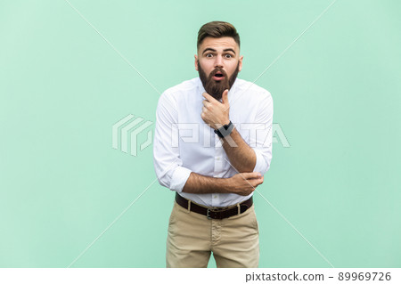 No way! Young adult with beard with shocked facial expression, holdings hands on chin. Indoor, studio shot No way! Young adult with beard with shocked facial expression, holdings hands on chin. Indoor, studio shot 89969726