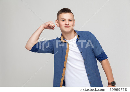 Happines boy showing masculinity and his strong at camera. Indoor shot, gray background Happines boy showing masculinity and his strong at camera. Indoor shot, gray background 89969758