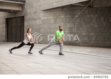 fitness, sport, exercising, training and people concept - couple doing triceps dip exercise on city street bench. fitness, sport, exercising, training and people concept - couple doing triceps dip exercise on city street bench. 89969766