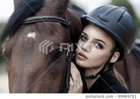 Closeup portrait of woman hugging hourse , looking at camera. Outdoor shot, sport and fashion concept. Closeup portrait of woman hugging hourse , looking at camera. Outdoor shot, sport and fashion concept. 89969781