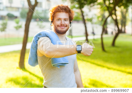 Young adult man showing smart watch or fitness tracker, smiling and looking at camera. Young adult man showing smart watch or fitness tracker, smiling and looking at camera. 89969907