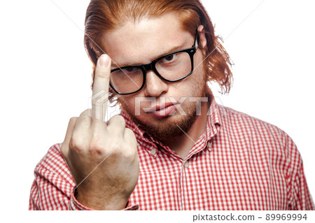 Angry bearded readhead businessman with red shirt and freckles looking at camera and showing middle finger . studio shot isolated on white. Angry bearded readhead businessman with red shirt and freckles looking at camera and showing middle finger . studio shot isolated on white. 89969994