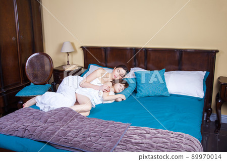 Mom and child hugging and sleeping together. Studio shot 89970014