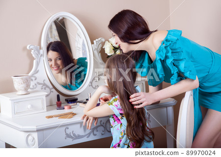 Mother hairdressing her preteen beautiful daughter at home. 89970024