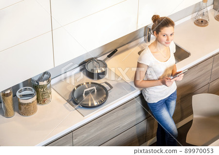 Beautiful young woman using a digital tablet in the kitchen. Beautiful young woman using a digital tablet in the kitchen. 89970053