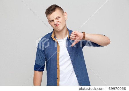 Dislike sign. Boy looking at camera and showing dislike sign. Studio shot Dislike sign. Boy looking at camera and showing dislike sign. Studio shot 89970068